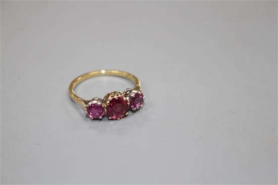 An 18ct and three stone ruby and garnet?? set dress ring, size M, gross 2.7 grams.